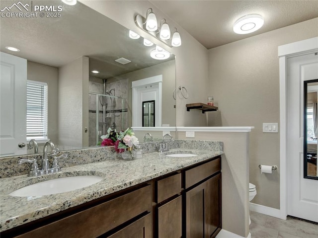 full bath with a sink, a shower stall, toilet, and double vanity