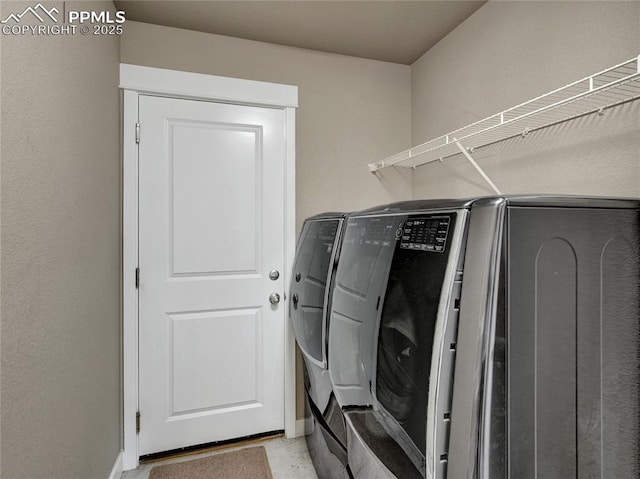 clothes washing area featuring laundry area, washing machine and clothes dryer, and baseboards