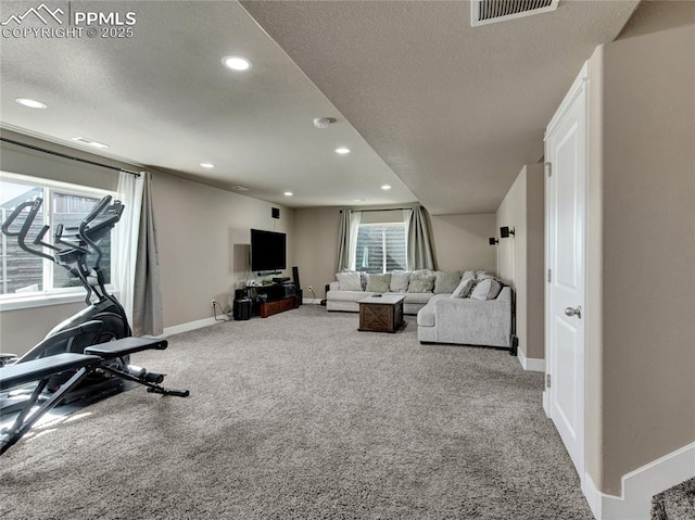 exercise room with carpet, a healthy amount of sunlight, visible vents, and a textured ceiling