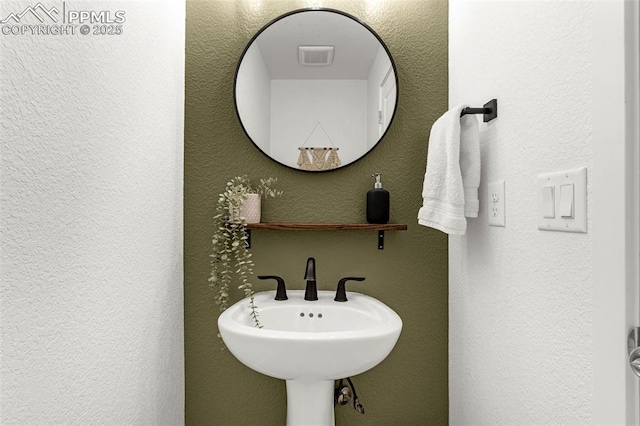 bathroom with a sink, visible vents, and a textured wall