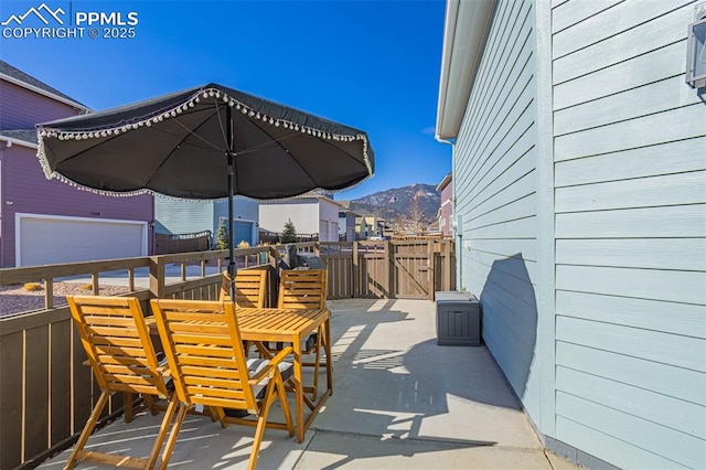 view of patio featuring outdoor dining space, a gate, fence, an outdoor structure, and a mountain view