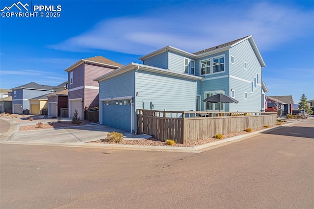 view of home's exterior with a garage, fence, a residential view, and driveway