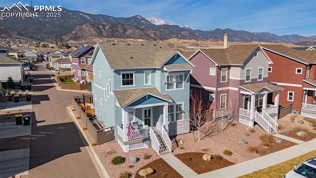 view of front facade with a porch, a residential view, a mountain view, and roof with shingles