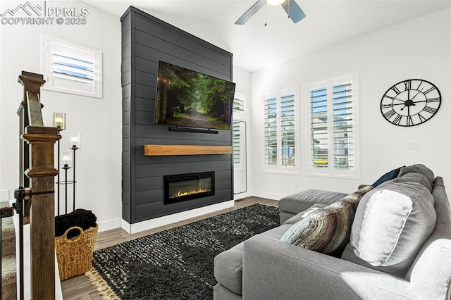 living room featuring a fireplace, baseboards, a ceiling fan, and wood finished floors