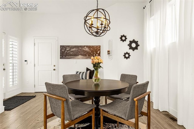 dining space with an inviting chandelier, a healthy amount of sunlight, and light wood finished floors