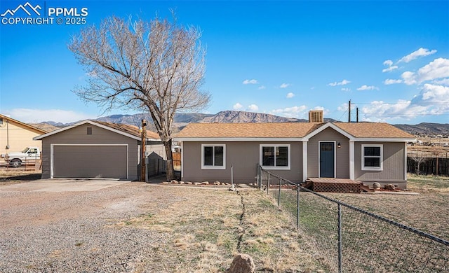 single story home with an outbuilding, fence, a mountain view, a garage, and driveway