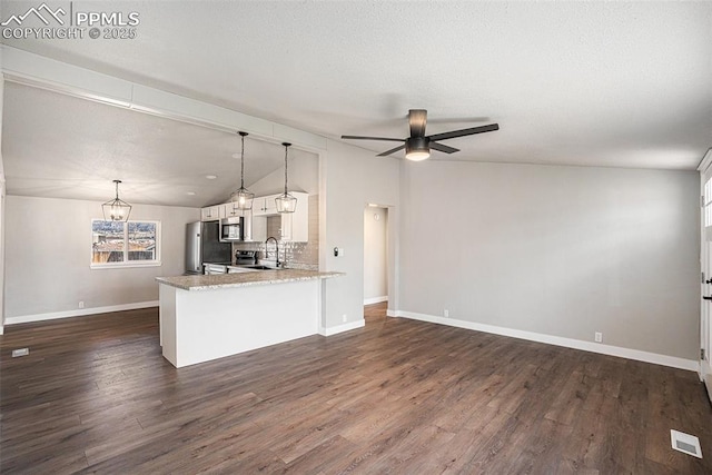 kitchen with white cabinets, lofted ceiling, appliances with stainless steel finishes, a sink, and ceiling fan with notable chandelier