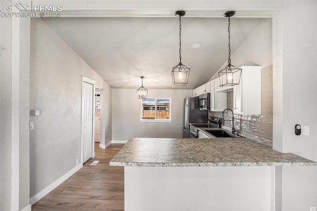 kitchen featuring dark wood-type flooring, a sink, white cabinets, vaulted ceiling, and appliances with stainless steel finishes