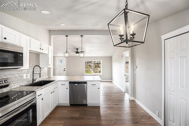 kitchen with stainless steel appliances, a peninsula, a sink, white cabinetry, and backsplash