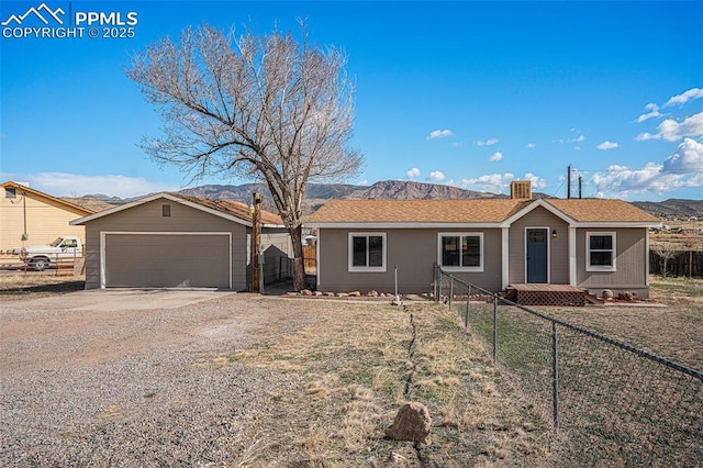 ranch-style house featuring a garage, concrete driveway, fence, and a mountain view