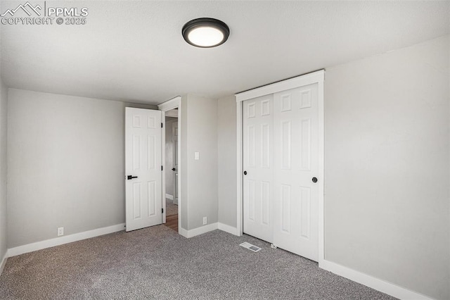 unfurnished bedroom with carpet floors, a closet, visible vents, and baseboards