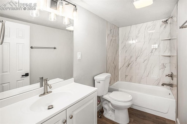 bathroom with a textured ceiling, toilet, wood finished floors, vanity, and washtub / shower combination