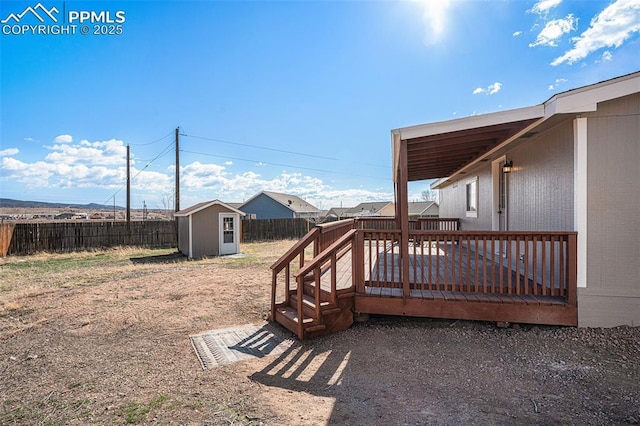 view of yard with an outbuilding, a storage shed, a fenced backyard, and a wooden deck