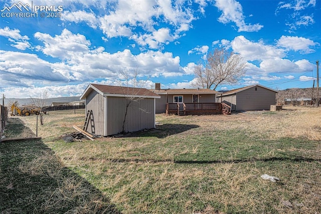 back of house with a wooden deck, fence, a yard, a shed, and an outdoor structure