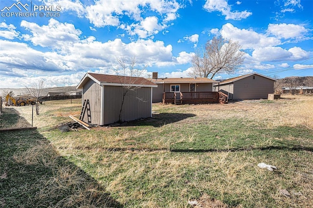 view of yard featuring an outdoor structure, a wooden deck, and a shed