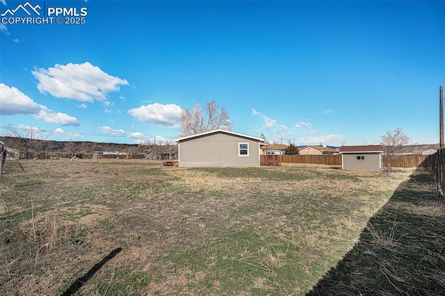 view of yard featuring an outbuilding, a storage unit, and fence