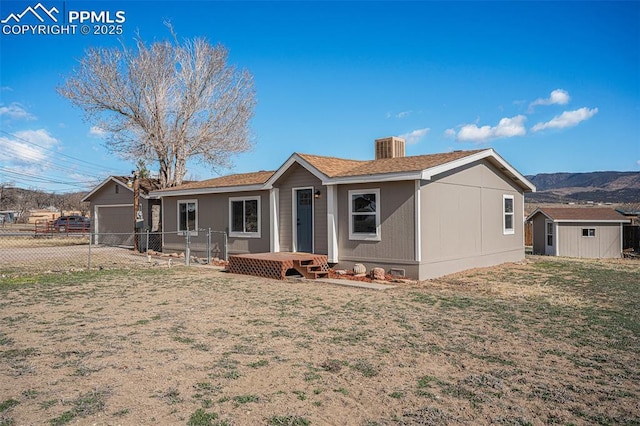 view of front of home featuring a garage, an outbuilding, a storage unit, fence, and a front lawn