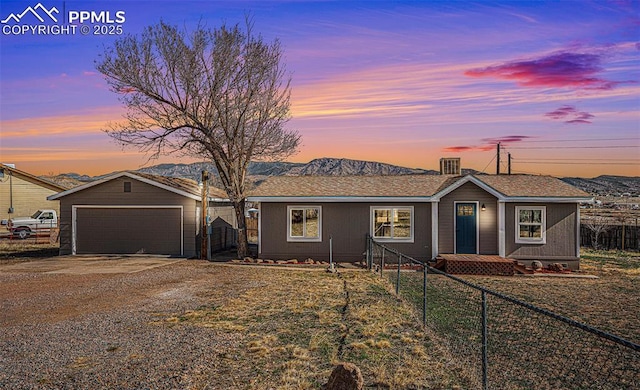 ranch-style house with a detached garage, an outdoor structure, fence private yard, and a mountain view