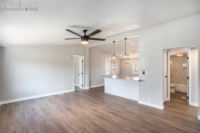 unfurnished living room featuring lofted ceiling, ceiling fan, a textured ceiling, and wood finished floors