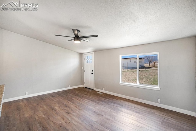 interior space with a ceiling fan, a textured ceiling, baseboards, and wood finished floors