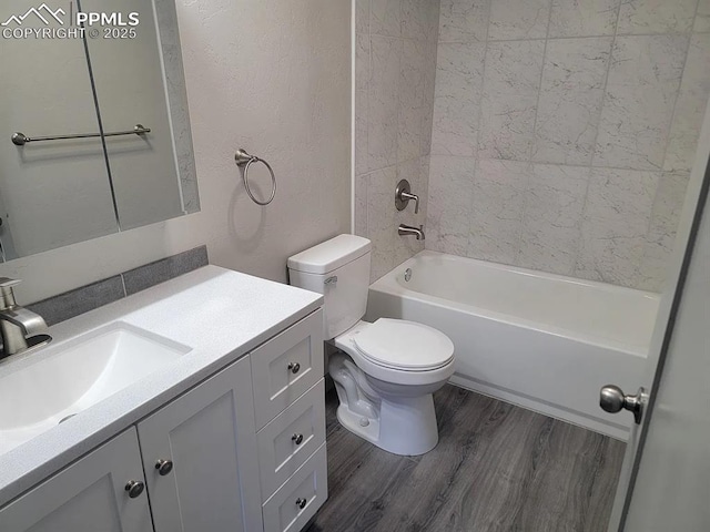 bathroom featuring a textured wall, toilet, wood finished floors, vanity, and  shower combination