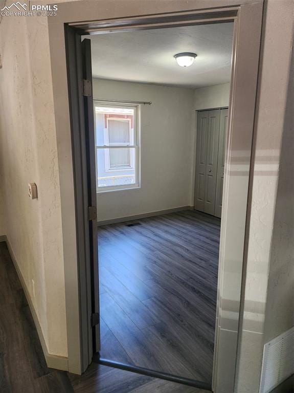 hallway with dark wood finished floors and baseboards