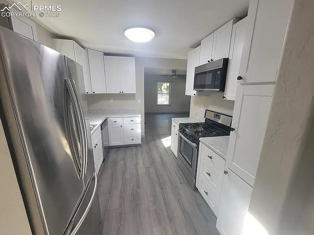 kitchen featuring light countertops, appliances with stainless steel finishes, light wood-type flooring, and white cabinets