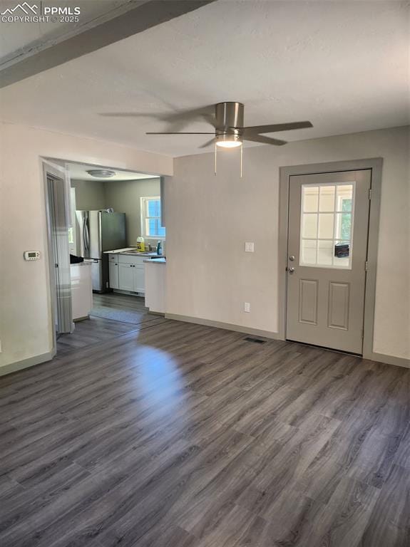 unfurnished living room featuring dark wood-type flooring, visible vents, and baseboards