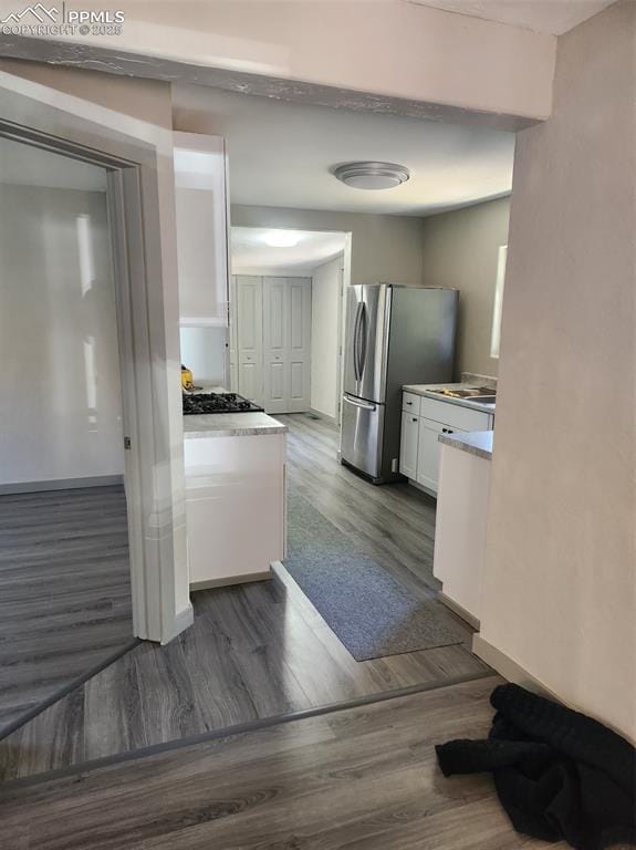 kitchen with dark wood-style floors, freestanding refrigerator, light countertops, and white cabinetry