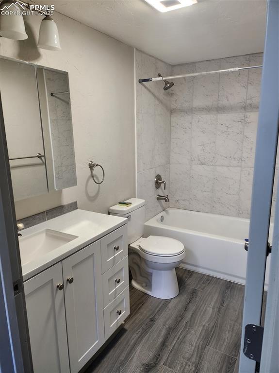 full bath with toilet, shower / bathing tub combination, wood finished floors, and vanity