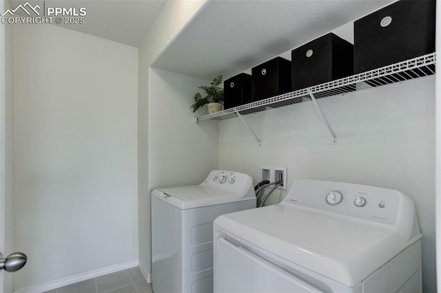 laundry area with light tile patterned floors, laundry area, washing machine and clothes dryer, and baseboards