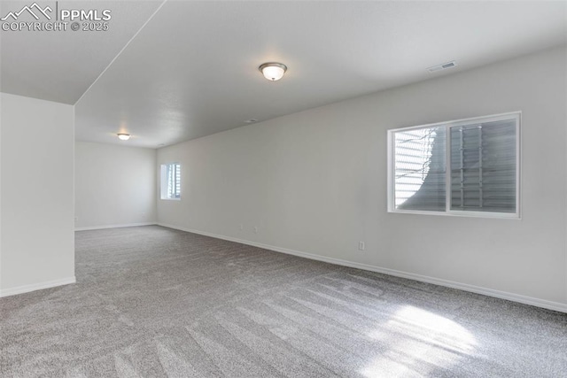 empty room with carpet, visible vents, and baseboards