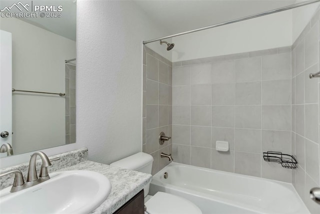 bathroom featuring a textured wall, shower / bathing tub combination, vanity, and toilet