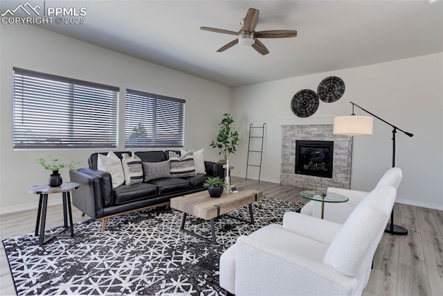 living area with ceiling fan, a fireplace, wood finished floors, and baseboards