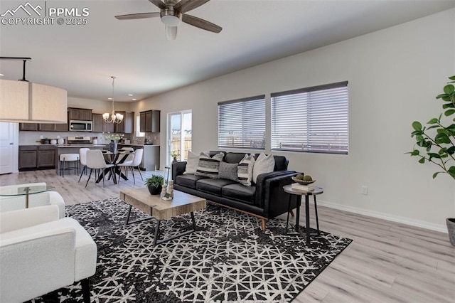 living area featuring ceiling fan with notable chandelier, recessed lighting, light wood-style flooring, and baseboards