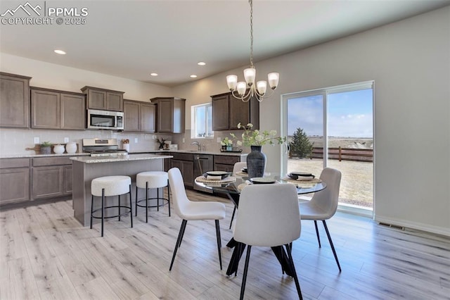 dining area with baseboards, visible vents, light wood-style flooring, a notable chandelier, and recessed lighting