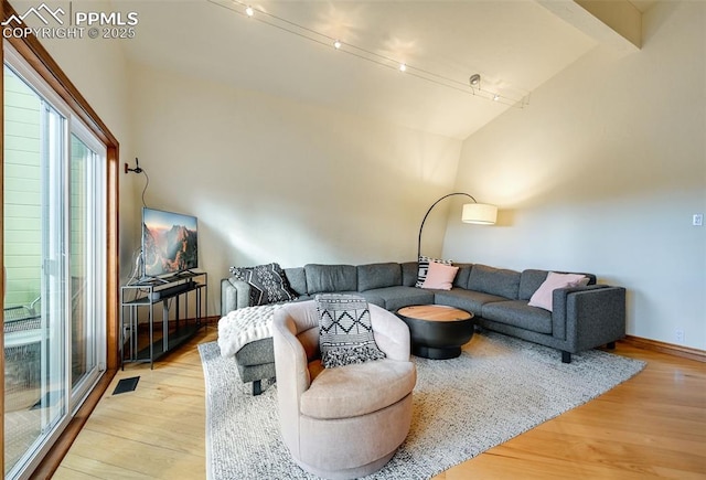 living area with rail lighting, visible vents, baseboards, and wood finished floors