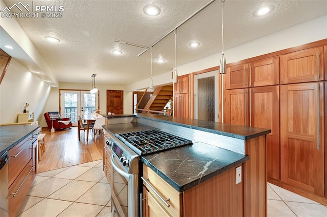 kitchen featuring dark countertops, light tile patterned floors, a kitchen island, and stainless steel appliances