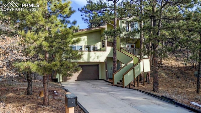 view of front of property featuring driveway, an attached garage, and stairs