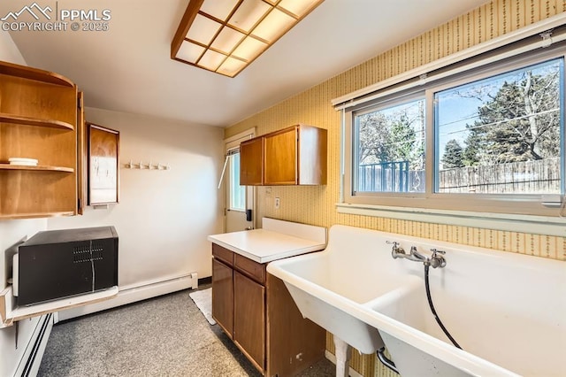 kitchen featuring wallpapered walls, brown cabinets, and a wealth of natural light