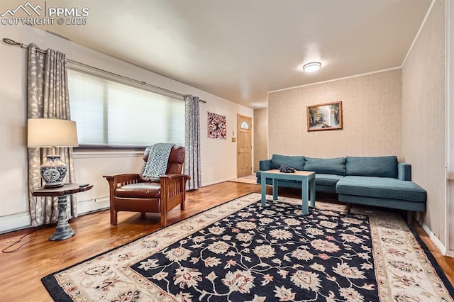 living area with a baseboard heating unit, baseboards, and wood finished floors