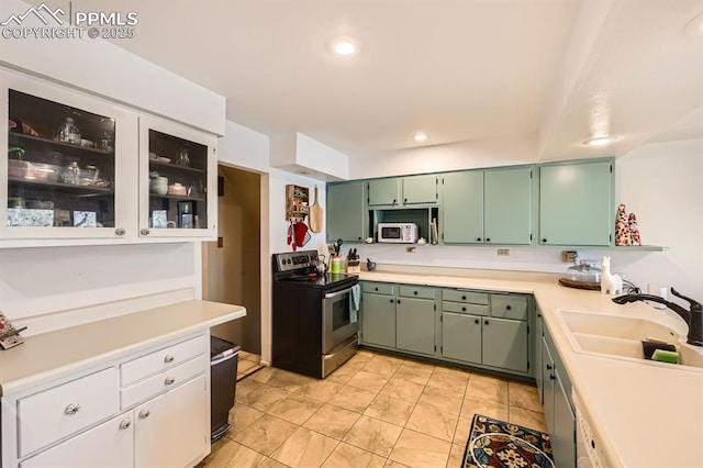 kitchen with a sink, white microwave, stainless steel electric range, and light countertops