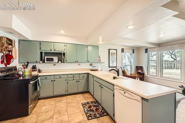 kitchen with light countertops, a peninsula, light tile patterned flooring, white appliances, and a sink