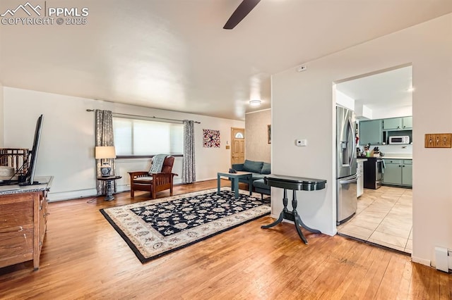 living room featuring a ceiling fan and light wood-type flooring