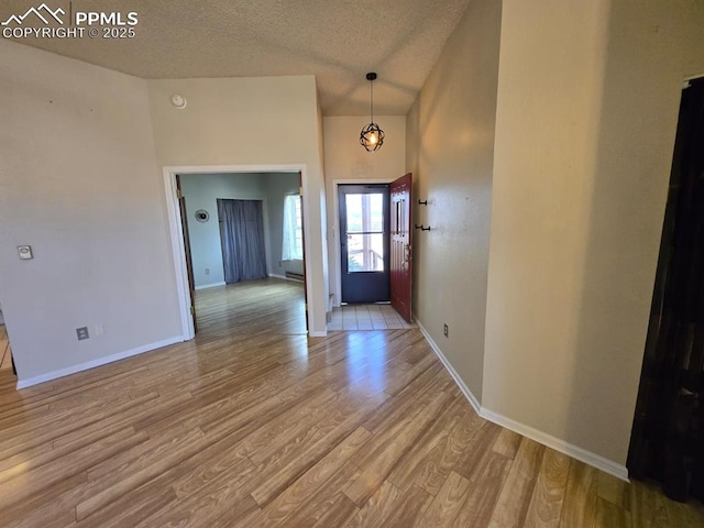 foyer entrance featuring a textured ceiling, baseboards, and wood finished floors