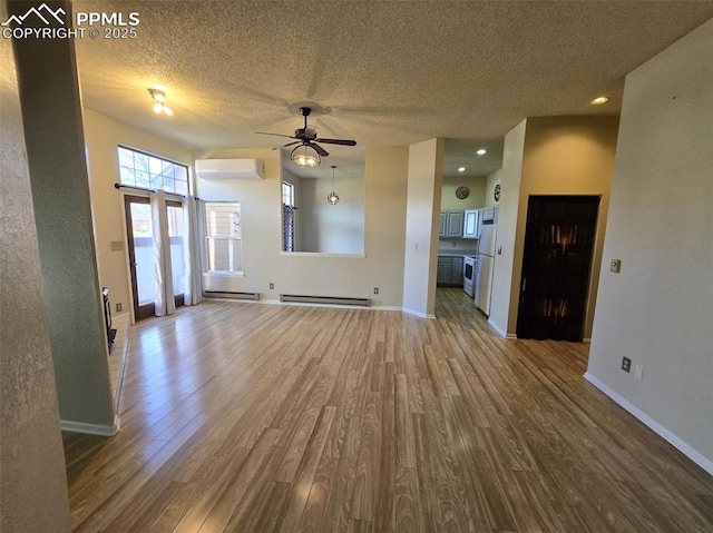 unfurnished living room featuring a textured ceiling, a baseboard radiator, wood finished floors, baseboards, and an AC wall unit