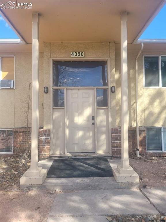 doorway to property with brick siding and stucco siding