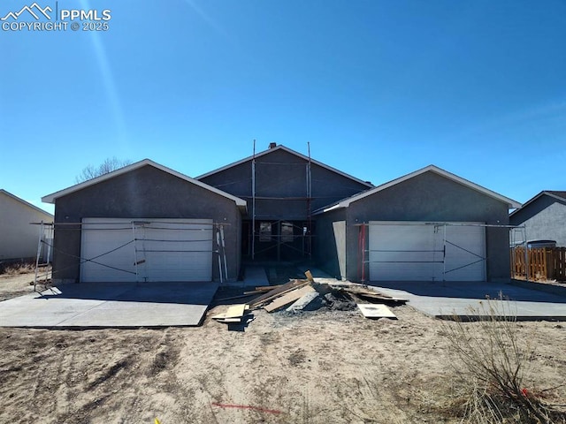 view of front of house featuring a garage, fence, and stucco siding