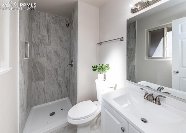 full bathroom with tiled shower, vanity, and toilet