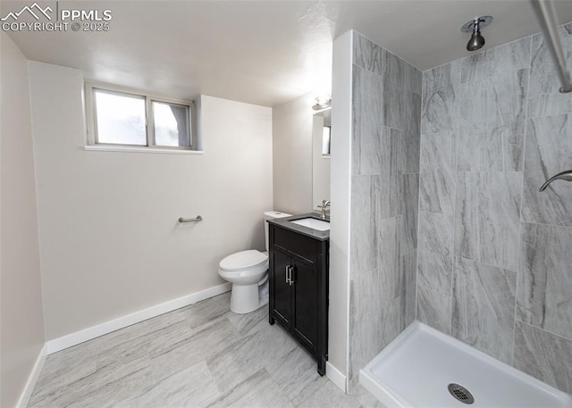 full bathroom featuring tiled shower, vanity, and baseboards